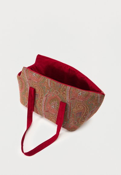 Tote bag with red fabric handles and paisley patterned body in red, gold, and green tones, interior lined with solid red fabric.