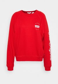 Czerwony sweter z okrągłym dekoltem, rękawami raglanowymi oraz ściągaczami u dołu i na rękawach. Na przodzie i rękawie widnieje logo i napis "Levi's".