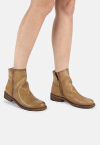 Braune Leder-Ankelstiefel mit glatter Textur, seitlichem Reißverschluss und niedrigem, gestapeltem Holzabsatz. Mit einem runden Zehendesign.