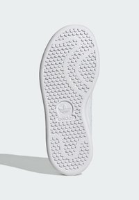 Balts gumijas apavu zole ar faktūras rakstu, kas piedāvā centrālo Adidas logotipu. Noapaļota forma ar izteiktām saķeres ribām.