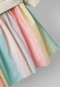 Moni kerros hame, jossa on pastellinvärinen gradientti: sininen, vaaleanpunainen, keltainen ja valkoinen, kultaisilla pilkkukuviolla kangasta kauttaaltaan.