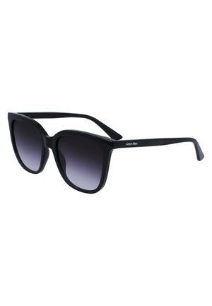 Black plastic sunglasses with a bold, oversized cat-eye shape. Gradient gray lenses and embossed logo detail on the temples.
