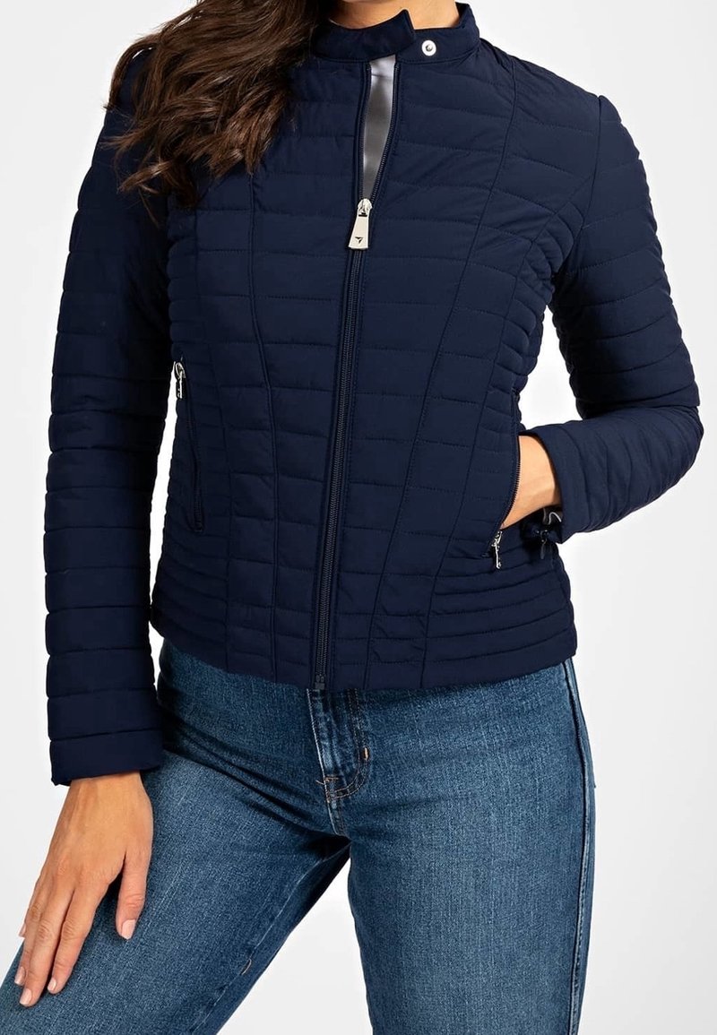 Navy quilted jacket with a zip front, high collar, and side pockets. Features a smooth accent at the neck and horizontal stitching detail.