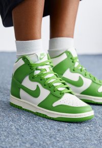 Höga sneakers i en blandning av vit och livlig grön läder, med gröna snören, texturerad tå och Nike-logotyp på sidan.