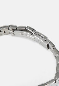 Silver metal watch band with interlocking links and fold-over clasp on white background.