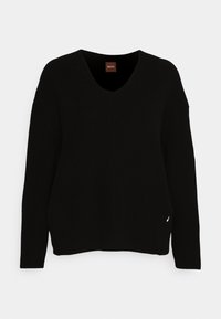 Svart stickad tröja med V-hals, oversized design, ribbad textur och en liten logotypaccent på sidan. Långa ärmar.