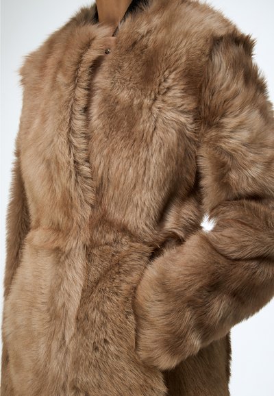 Cappotto in ecopelliccia tonalità marrone caldo, caratterizzato da una texture morbida, colletto rotondo, tasche laterali e chiusura a scatto discreta.