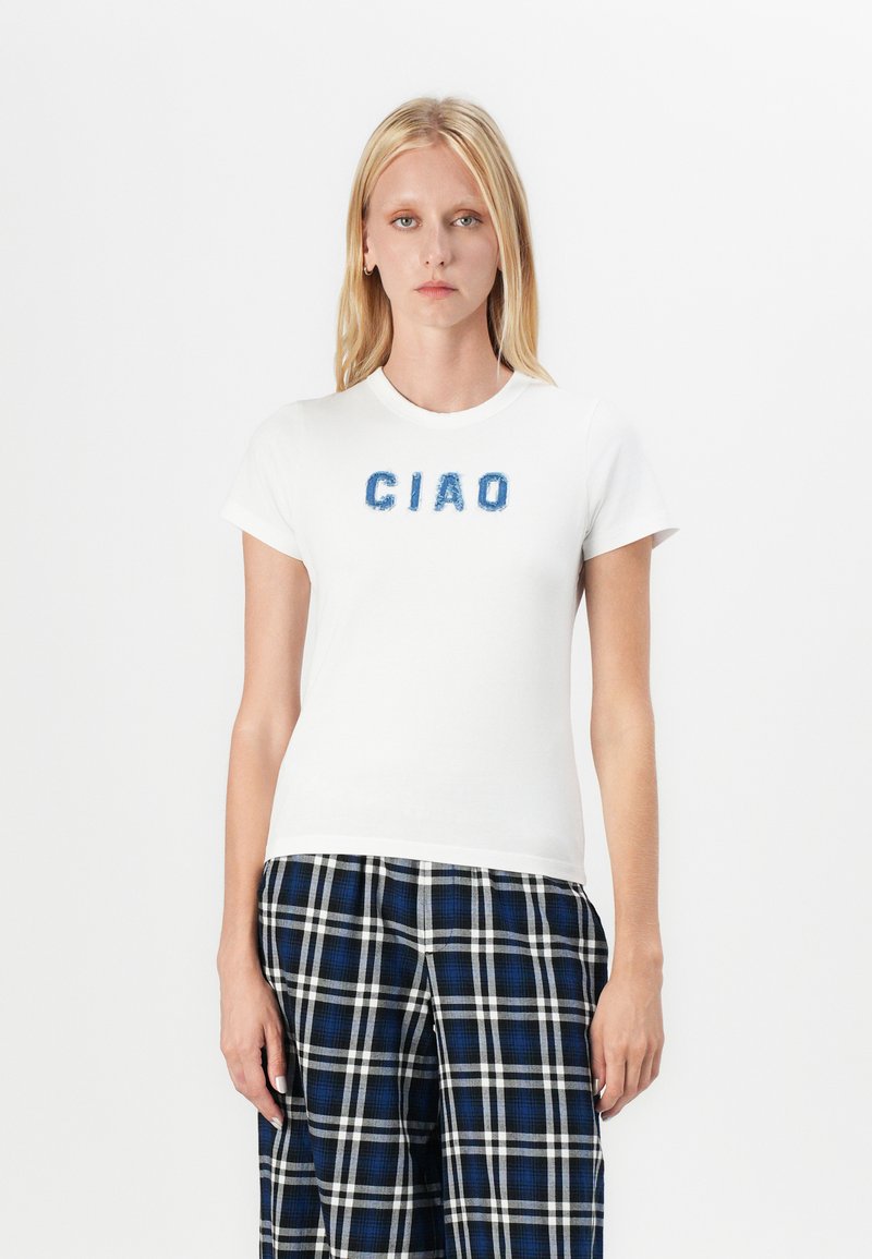 Hvit bomulls t-skjorte med blå, fluffy "CIAO"-tekst på forsiden. Korte ermer og rund hals, sammen med bukser i blå og svart rutete mønster.