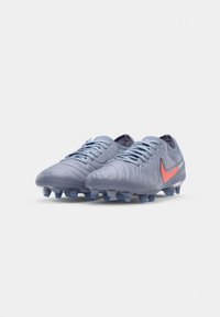 Light blue football boots with textured upper, contrasting orange swoosh logo, six studs for traction, and a lace-up closure.