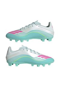 Chaussures de football blanches avec semelles turquoise et bandes rose, ornées de motifs ondulés bleu clair et jaune sur les côtés.