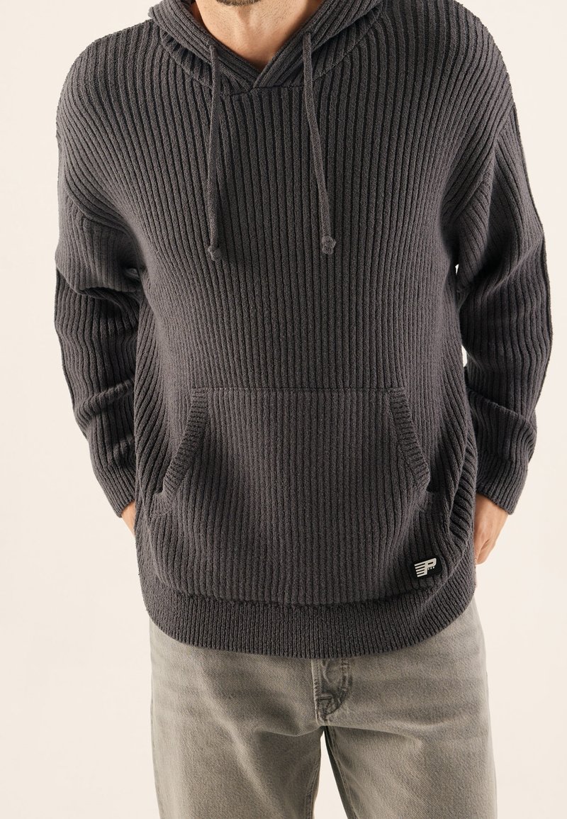 Dunkelgrauer, gerippter Hoodie mit V-Ausschnitt und Kordeln, ausgestattet mit einer Fronttasche und einem kleinen Logo auf der unteren Seite. Weicher Stoff.