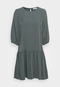 Vestido verde oscuro, de longitud a la rodilla, con escote redondo, mangas largas abullonadas y un dobladillo con volantes en capas. Confeccionado en una tela ligera.