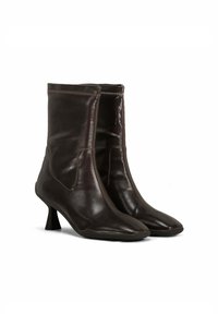 Bottines en cuir marron avec un bout pointu, un petit talon conique et un minimum de détails de couture sur le dessus. Texture lisse et brillante.