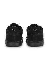 Czarne zamszowe sneakersy o matowym wykończeniu, z gładką czarną gumową podeszwą i małym srebrnym logo na pięcie.