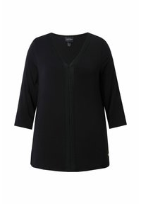Schwarze Tunika mit V-Ausschnitt, ¾-Ärmeln und strukturiertem Mittelteil. Sie verfügt über einen glatten Stoff und einen goldenen Akzent nahe dem Saum.