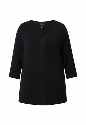 Musta tunika, jossa on V-pääntie, ¾-hihat ja teksturoitu keskiosa. Ominaisuuksiin kuuluu sileä kangas ja kultainen yksityiskohta helman lähellä.