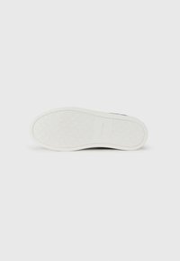 Black sneaker outsole with a textured white rubber sole, featuring a diamond pattern and "Calvin Klein" branding.