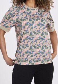 Top de manga corta con estampado floral en varios colores, incluyendo rosa, verde y azul, con un cuello y dobladillo en color beige. Textura de tela suave.