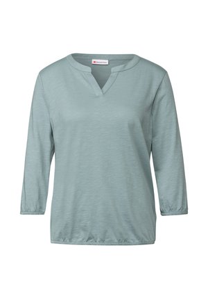 Light blue, long-sleeve V-neck top with a relaxed fit, gathered sleeves, and soft textured fabric. Minimalist design with no patterns.