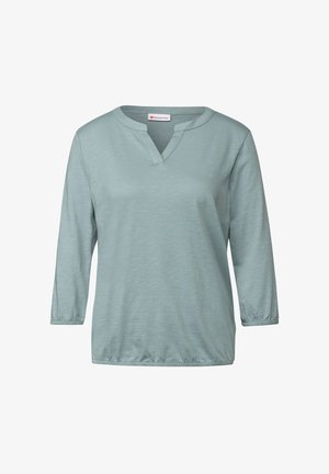 Haut bleu clair à manches longues et décolleté en V, avec une coupe décontractée, des manches froncées et un tissu doux et texturé. Design minimaliste sans motifs.