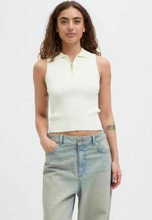 Top senza maniche, con colletto alto e righe in giallo chiaro, caratterizzato da una zip frontale con un tirante circolare. Abbinato a jeans larghi di un blu pallido.