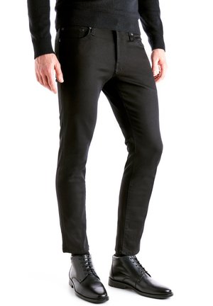 Jeans noirs à coupe ajustée, en denim, avec poches avant et fermeture éclair. Portés avec des bottes noires à lacets pour un look soigné.
