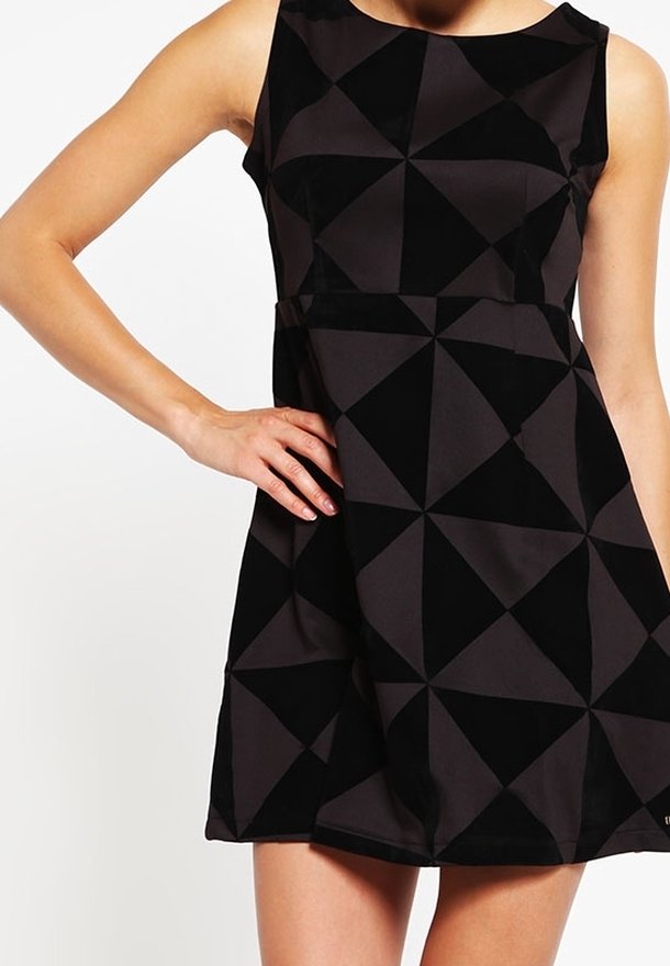 Une robe noire sans manches avec un motif géométrique en losanges, fabriquée à partir d'un tissu doux, avec un corsage ajusté et une jupe évasée.