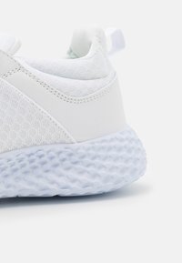 Baskets blanches avec une tige texturée, des accents lisses et une semelle épaisse en forme de bulle avec une finition semi-transparente.