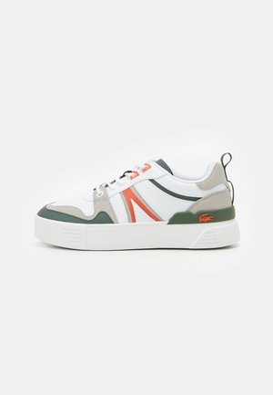 Witte sneaker met groene en beige accenten, oranje details, dikke witte zool en een lusje aan de hiel.