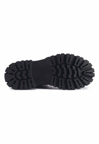 Suela de zapato de goma negra con profundas ranuras y un patrón resistente para tracción. Centro liso con forma curvada.