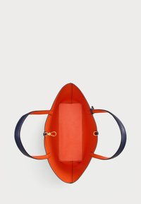 Ωβάλ τσάντα με ναυτικό δερμάτινο εξωτερικό και ζωντανό πορτοκαλί εσωτερικό. Διαθέτει υφή αποθηκευτικό χώρο και κομψές λαβές.
