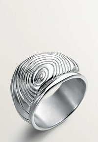 Anillo de plata con una superficie texturizada que asemeja patrones de vetas de madera concéntricas, con una banda ancha y un acabado pulido.