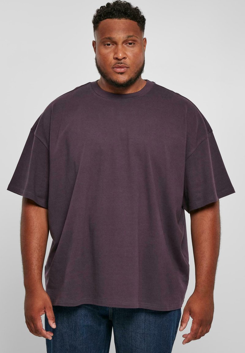 Tricou supradimensionat de culoare violet închis, fabricat din bumbac, cu guler rotund și mâneci scurte. Textură netedă și croială lejeră.