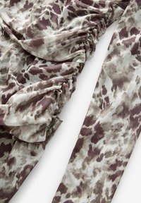 Material patterned în tonuri de violet și crem, cu un design plisat, având o textură netedă și o cădere fluidă, potrivit pentru îmbrăcăminte.