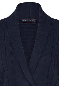 Cárdigan de punto en color marino con patrones de trenzas, cuello chal y textura acanalada; etiqueta "FELIX HARDY" cosida en el interior del cuello.