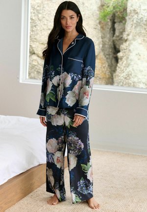Set de pijamale floral bleumarin, format dintr-un top cu model și margini albe și pantaloni largi asortați, confecționat dintr-un material moale.