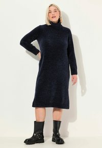 Abito a collo alto navy in maglia con maniche lunghe, polsini e orlo a costine. Abbinato a stivali neri robusti con dettaglio di cinturino e fibbia.