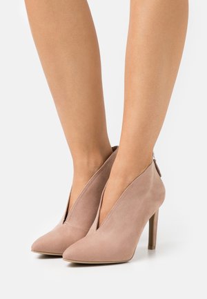 Rosa Wildleder High Heels mit spitzem Zeh, featuring ein tief ausgeschnittenes Design und einem Reißverschluss auf der Rückseite, auf einem weißen Hintergrund präsentiert.