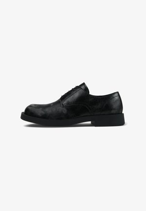 Black leather lace-up men's dress shoe with a slightly textured surface and a thick black sole, shown from the side on a white background.