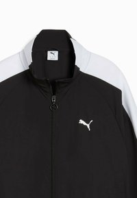 Czarna i biała kurtka zapinana na zamek z kołnierzem typu stand, z białym logo Puma na piersi i gładką fakturą.