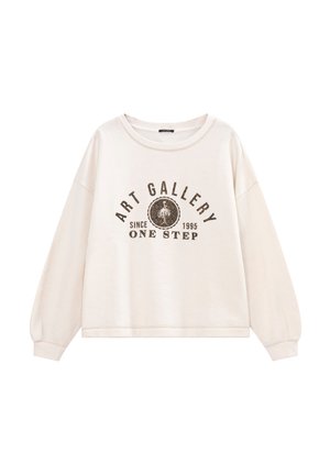Cremefarbener, übergroßer Pullover mit langen Ärmeln, rundem Ausschnitt und einem grafischen Aufdruck in Braun mit dem Text "KUNSTGALERIE SEIT 1995 EIN SCHRITT."