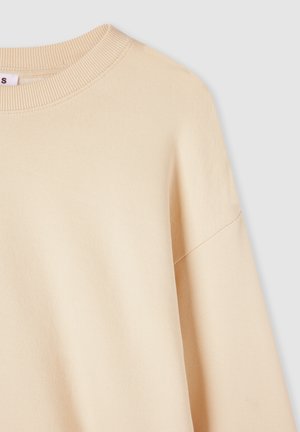 Jasno beżowy, oversize'owy sweatshirt z karbowanym okrągłym dekoltem i opuszczonymi ramionami, wykonany z miękkiej, strukturalnej tkaniny.