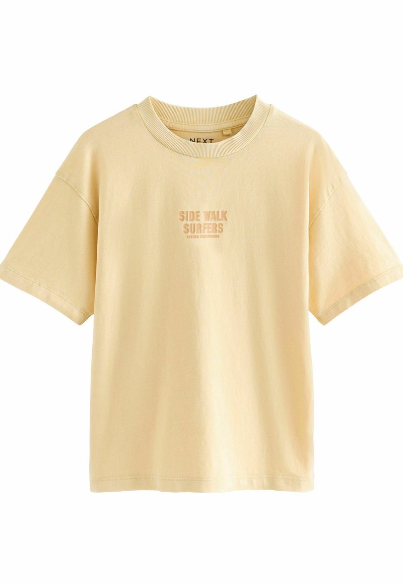 T-shirt jaune à manches courtes avec un col rond et un graphique "SIDE WALK SURFERS" imprimé dans une teinte légèrement plus foncée. Tissu doux, coupe décontractée.