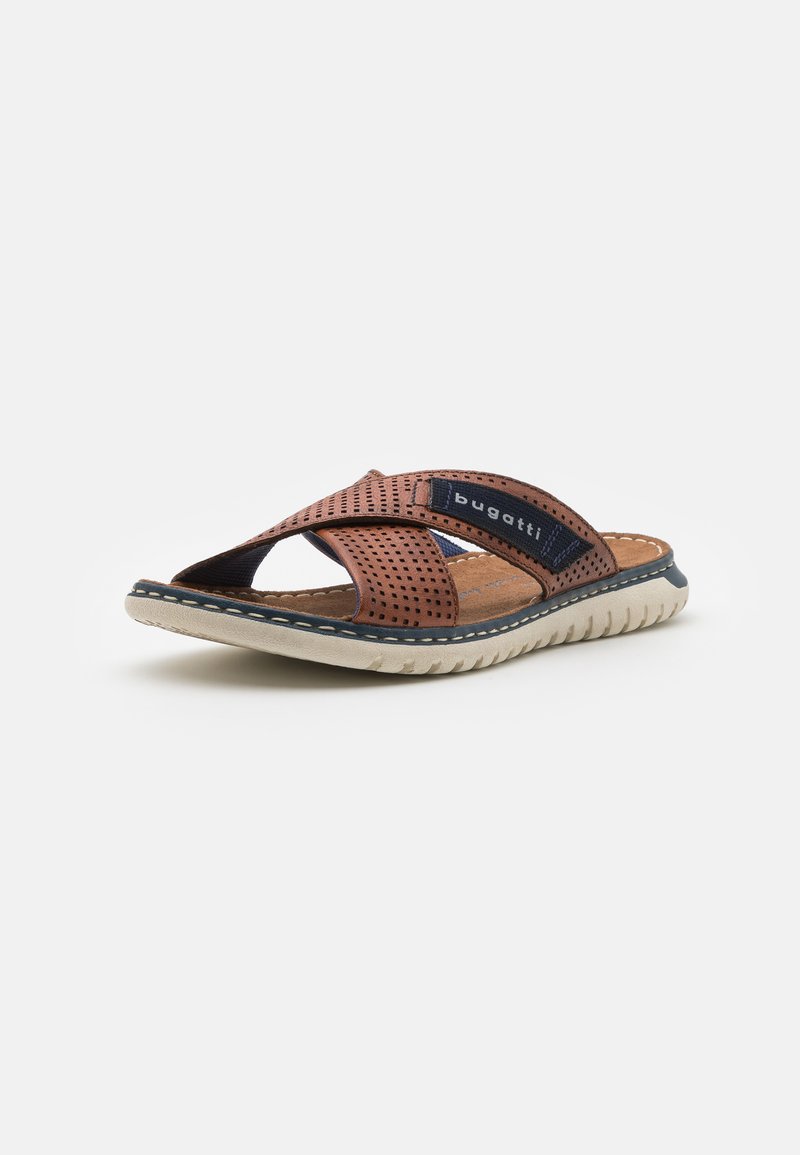 Braune Leder-Sandalen mit überkreuzten Riemen, Perforationen, gepolstertem Fußbett und einer strukturierten Gummisohle für Grip und Komfort.