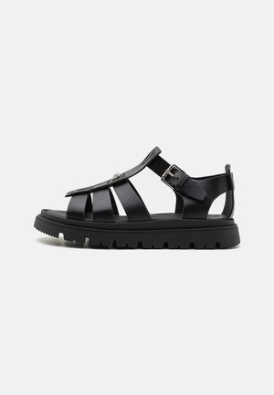 Sandal nera con un design intrecciato, realizzata in materiale testurizzato, con una suola spessa e fibbia regolabile per una vestibilità sicura.