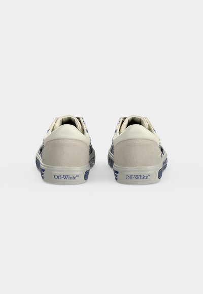 Ζευγάρι λευκά χαμηλά sneakers με μπλε κείμενο "Off-White" στη φτέρνα, εμφανιζόμενα από πίσω σε απλό ανοιχτό γκρι φόντο.