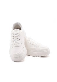 Sneakers bianchi con materiale sintetico liscio, punta arrotondata, suola in gomma piatta e design con lacci. Cuciture minime e senza loghi visibili.