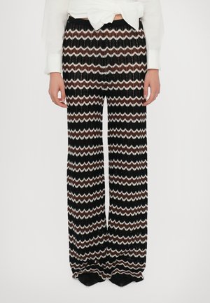 Weite, gestrickte Hosen mit einem Zickzackmuster in Schwarz, Weiß und Braun. Weicher Stoff mit einer entspannten Passform und elastischem Bund.