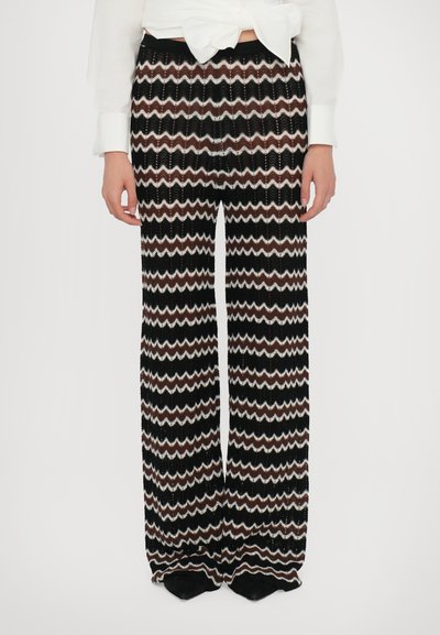 Pantalones de punto de pierna ancha con un patrón de zigzag en negro, blanco y marrón. Textura suave con un ajuste relajado y cintura elástica.