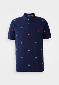 Námořnické modré polo tričko s krátkým rukávem, které má vícoloré vyšívané vlajky a červené logo na levé hrudi. Dvouknoflíková léga.